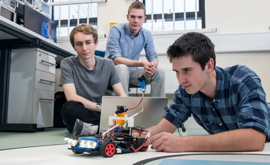 Two male wireless communications engineering students testing a robot