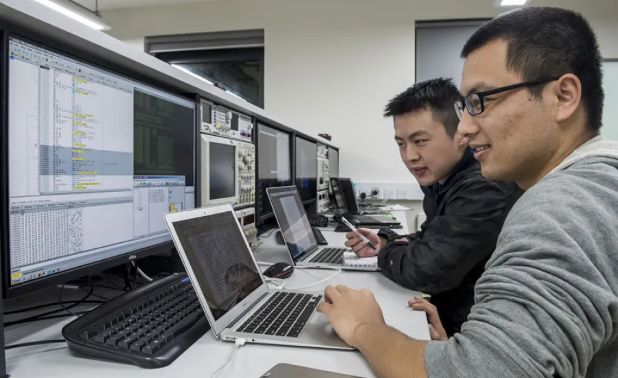 Two cyber security researchers work at a bank of computer screens