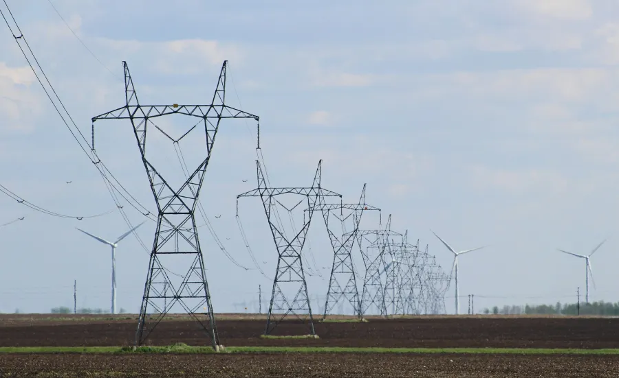 Transmission towers and wind turbines on a field