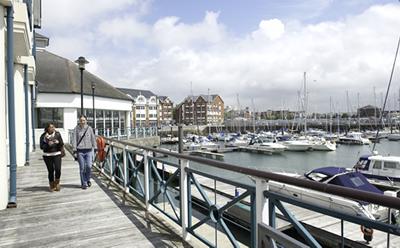 Two people walk beside a harbour