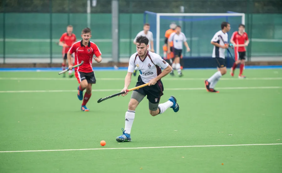 Men's hockey match being played on artificial pitch.