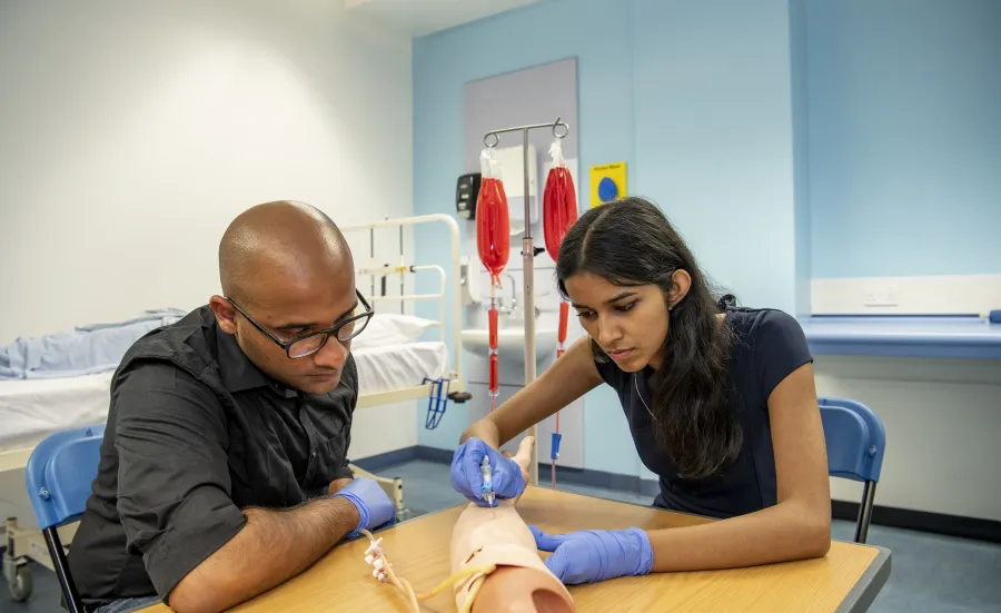 Medical students practice on a prosthetic arm in the clinical skills suite