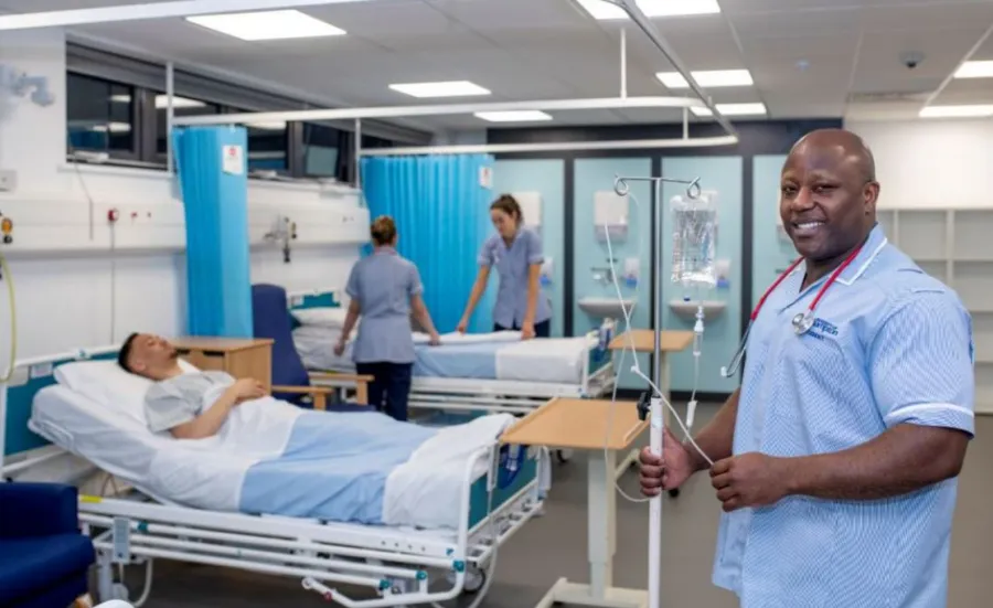 Nursing students working on a simulated ward with beds and drip