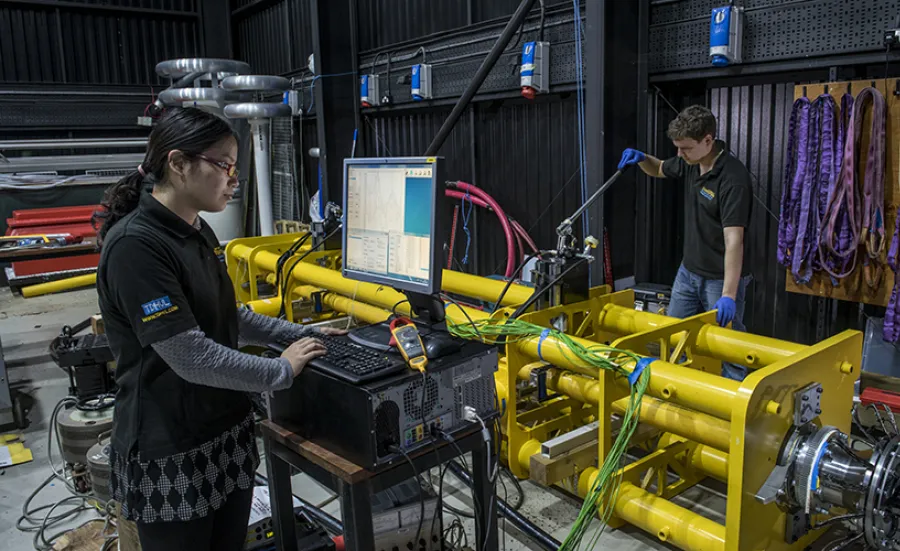 Two students operating a piece of heavy equipment in the high voltage lab.