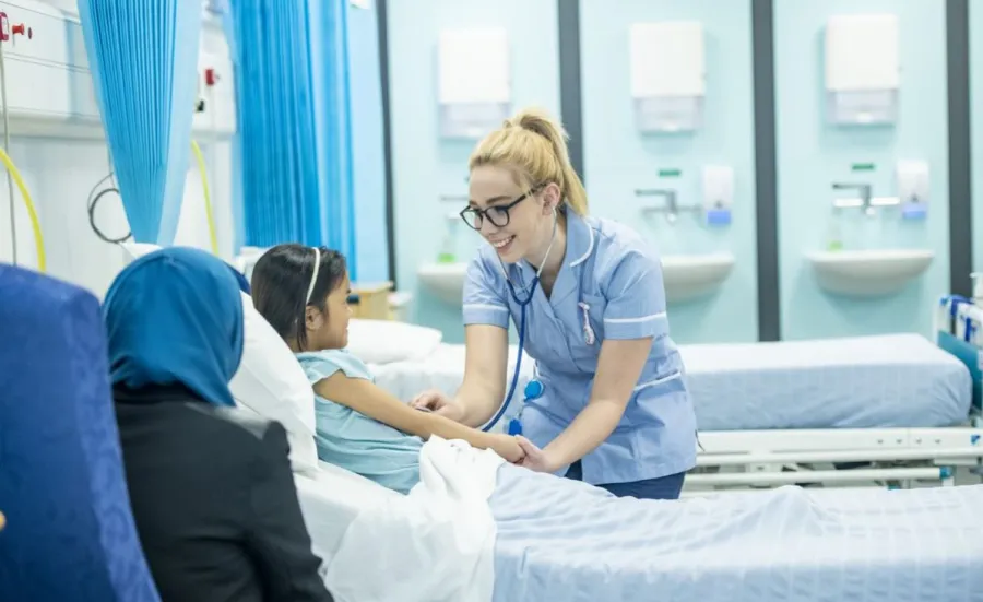 Nursing student tends to child patient at their bedside
