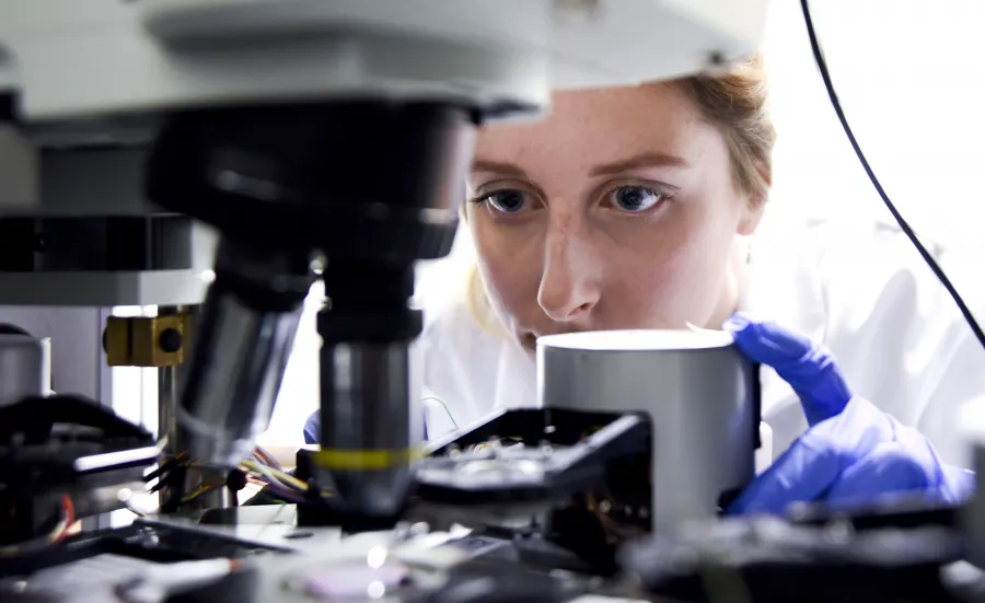 Doctor Katrina Morgan conducting research into novel glass beneath a microscope.