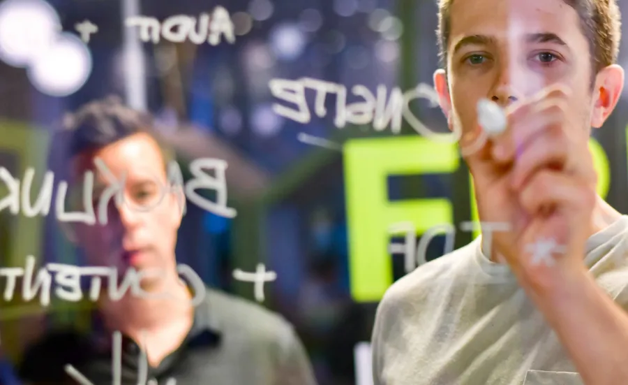 A man writing ideas on a glass wall with a marker pen