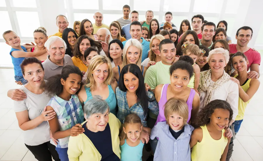 A stock photo of a large group of people of all ages, genders and ethnicities smiling up at the camera.