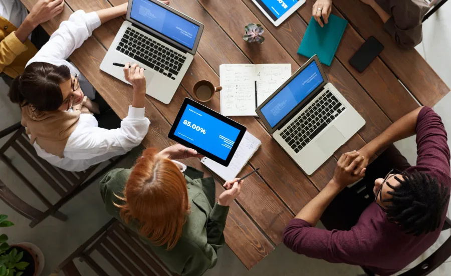 looking downwards at people sitting around a table with their laptops