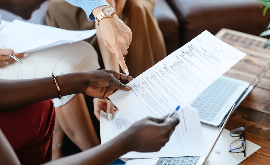 Pexels image showing hands holding a sheet of paper and pen, in a formal meeting