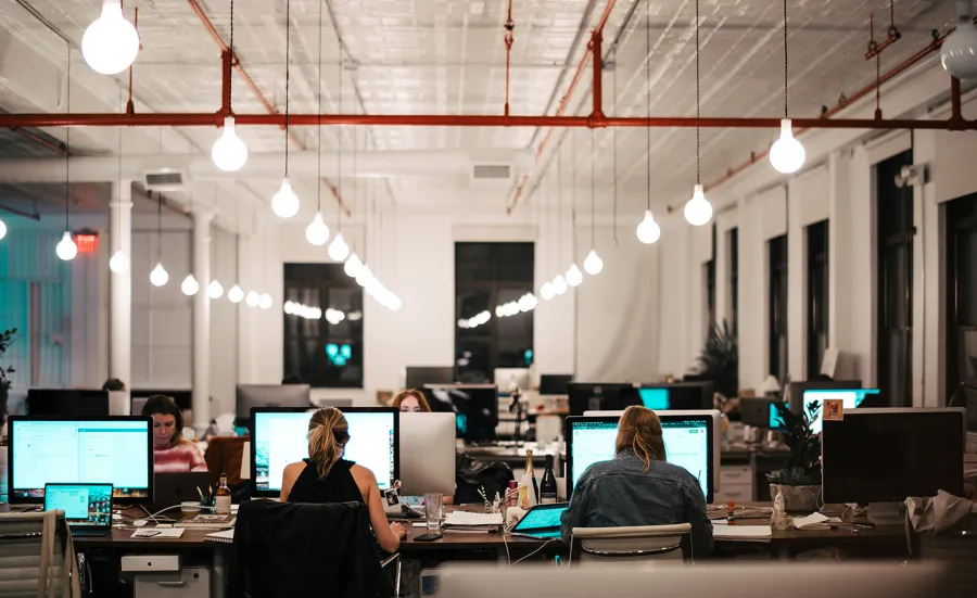 Unsplash image of seated workers using computers, in a modern office with high ceilings