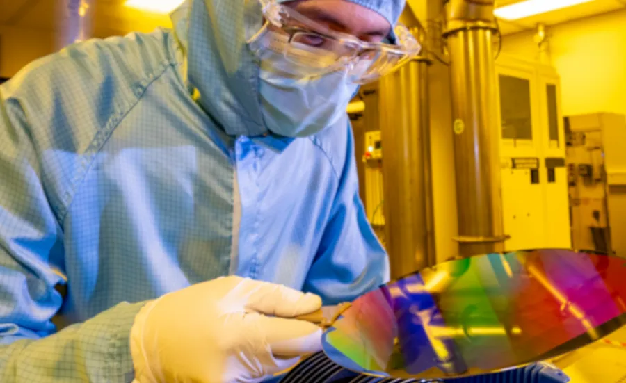 A researcher in a cleanroom suit with a 200mm wafer in the nanofabrication cleanroom