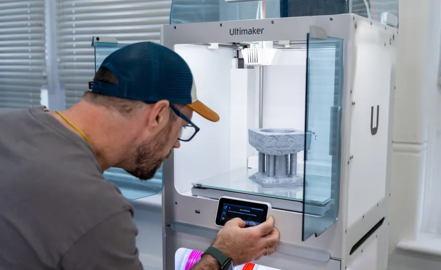 A technician adjusts the settings on the control panel of a 3D printer