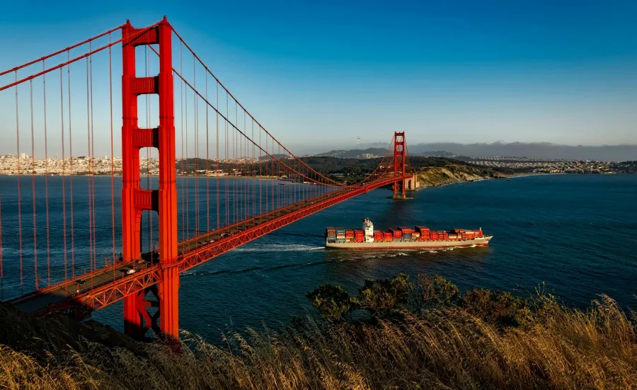 A container ship sailing under the San Fransisco Golden Gate Bridge