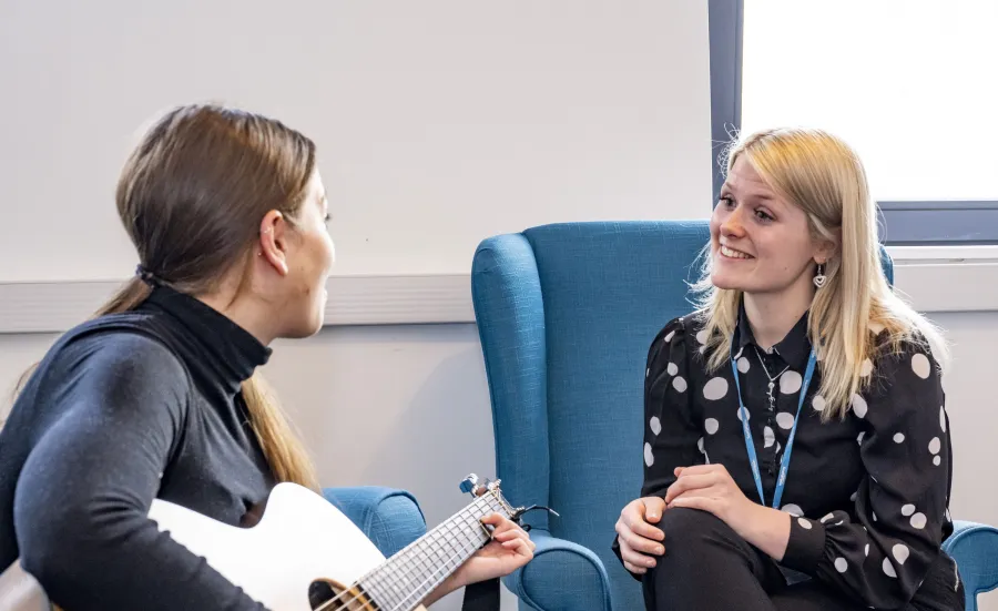 Two people sitting with a guitar