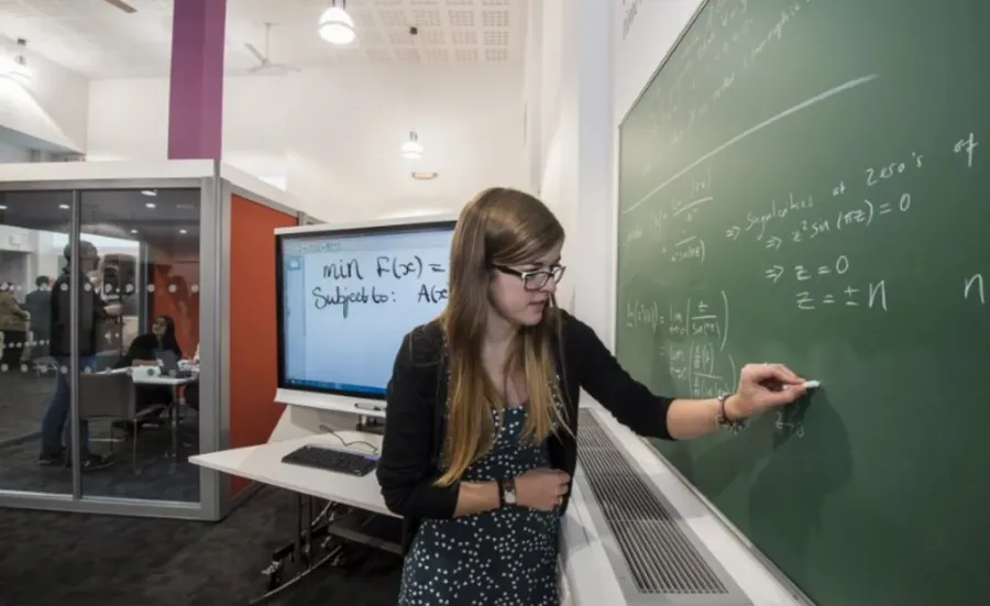 A student works on a maths problem using a blackboard in the maths student centre.