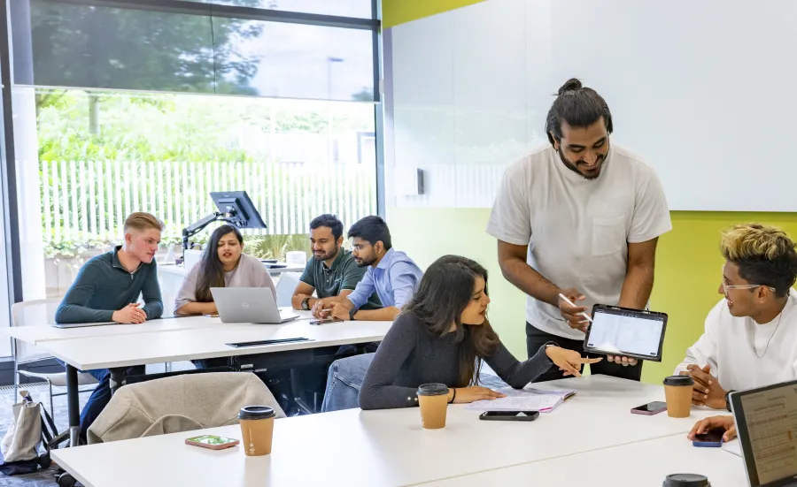 Students watching a lecturer demonstrating work on a tablet