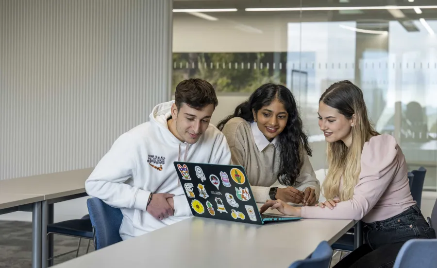 Three students with a laptop