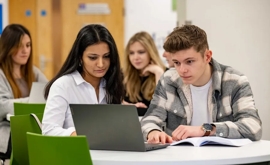 Two students at a table with a laptop