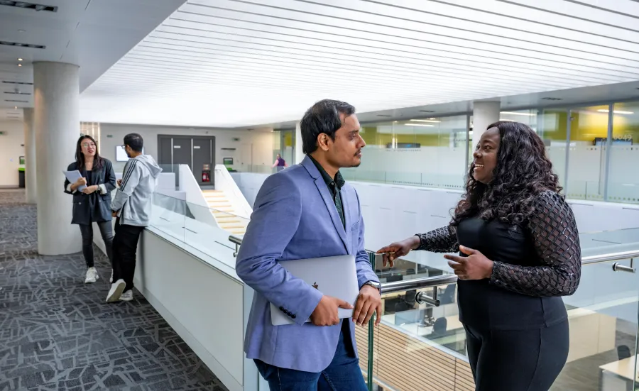 Students chatting on a balcony overlooking the MBA suite