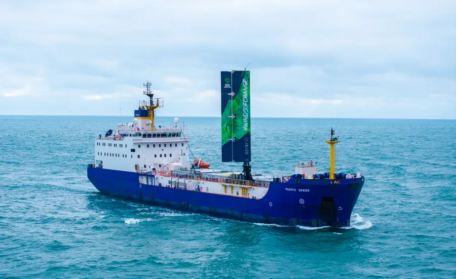 A large cargo vessel sailing on the ocean. It has a 20 metre-high wing sail. 