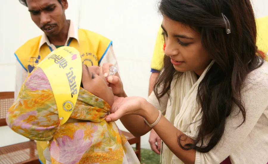 Woman giving a child a polio vaccination