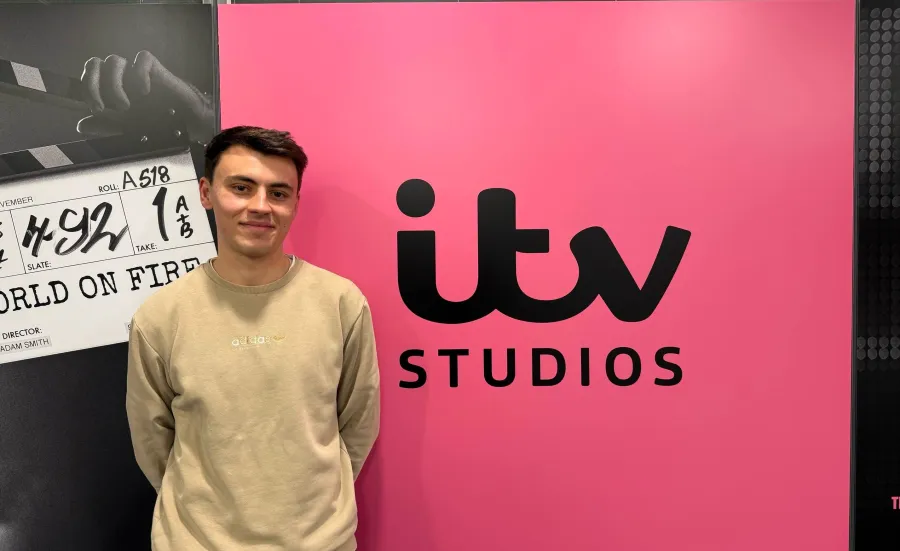 BA Spanish and Linguistics Graduate, Joe Dobinson standing by a sign for ITV studios.