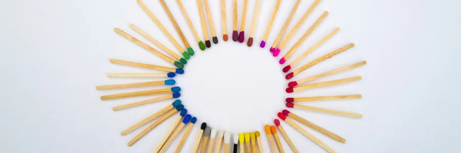 A colorful array of matchsticks arranged in a radial pattern to form a rainbow gradient on a white background.