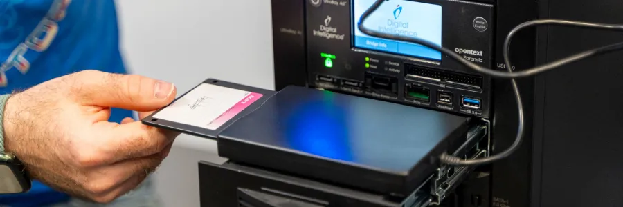 A hand inserts a floppy disc into the hard-drive of a high-powered PC.