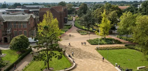 Aerial view of campus buildings, trees and courtyard area on a sunny day.