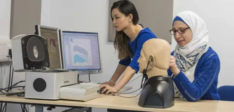 2 students conducting a hearing test on a dummy.