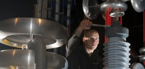 A student using a spanner to adjust a large piece of equipment in the high voltage lab.