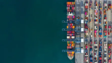 Top-down view of colourful shipping containers at a seaport with clear water