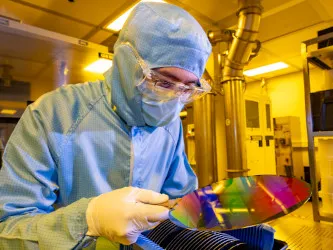 A researcher in a cleanroom suit with a 200mm wafer in the nanofabrication cleanroom