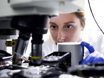 Doctor Katrina Morgan conducting research into novel glass beneath a microscope.