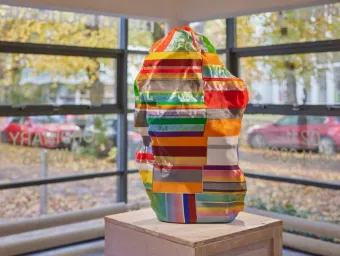 A colourful sculpture, titled Cornpick by Ian Dawson, sits on a plinth in the window of Winchester Gallery