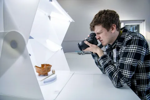 A student photographing small archaeological objects in a dedicated photography studio.