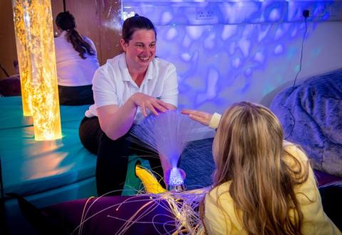 A healthcare students works with their young client in the multisensory room
