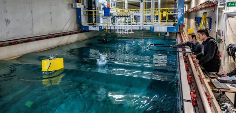 A student uses the 138m towing tank to investigates a buoy's hydrodynamic performance while a researcher offers advice