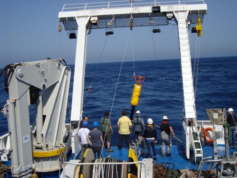 A team onboard a ship lifts an instrument into the water to measure ocean turbulence