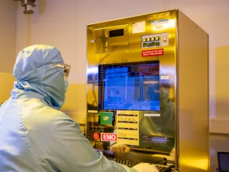 A researcher wearing a cleanroom suit uses the deep ultraviolet (DUV) scanner facility