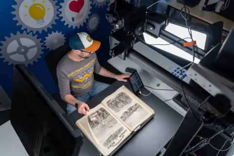 A person is shown using scanning equipment to scan a historic document