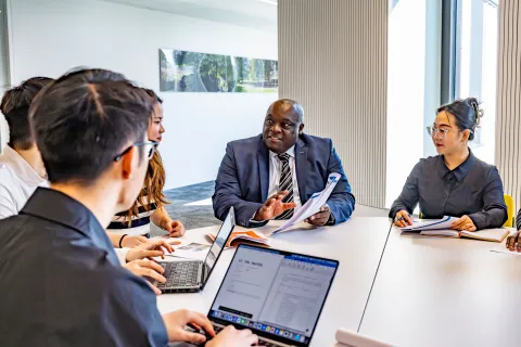 Professor Ven Tauringana and students dicussing at table
