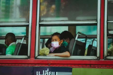 Girl with mask sitting inside bus