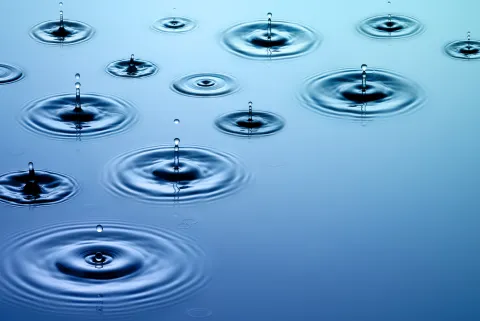 Droplets of water falling on water along with their concentric wave patterns