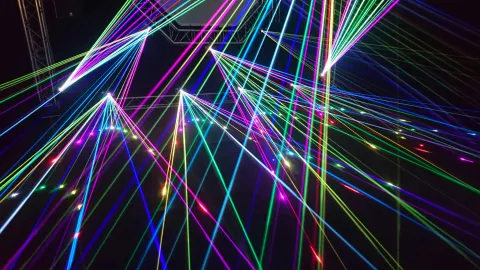 Colourful laser beams intersecting against a dark background.