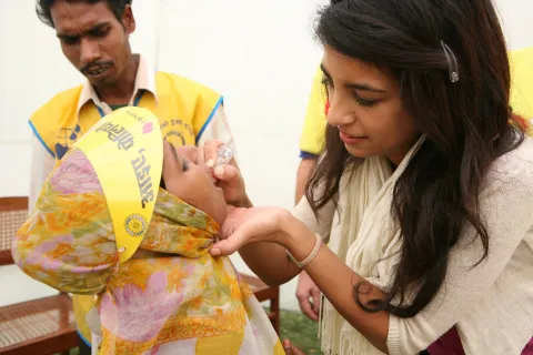 Woman giving a child a polio vaccination