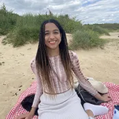 Laureen Adewusi, BM4 student, sitting at the beach smiling at the camera.