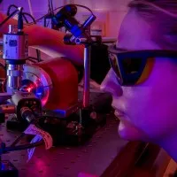 Female photonics degree student wearing glasses and staring into machine