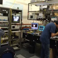 Two researchers from the optical fibre communications group at work against a backdrop of complex equipment 